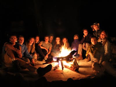 Group of students relaxing around a campfire