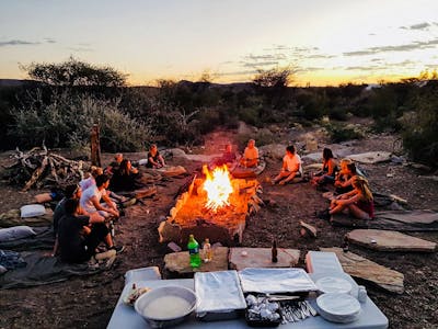 Group of ACE volunteers relaxing around the campfire in the late afternoon