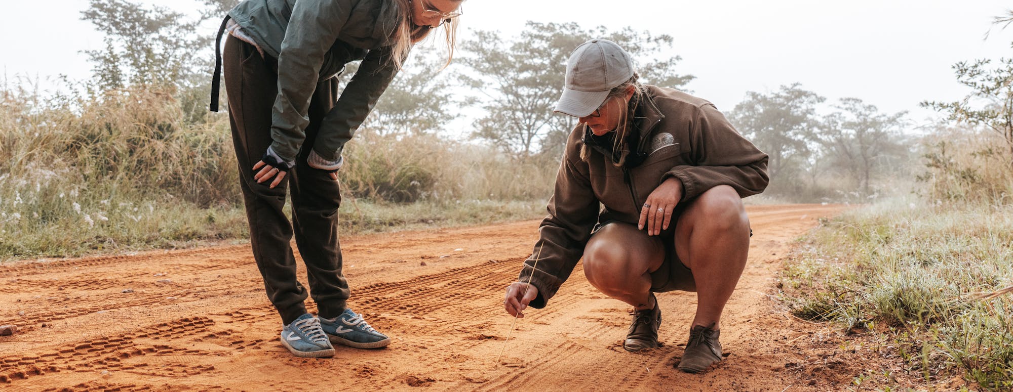 Two females looking at animal tracks