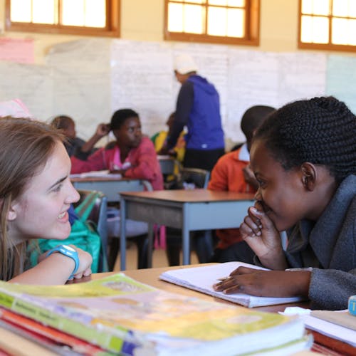 An ACE student working, learning and teaching with a student in a school