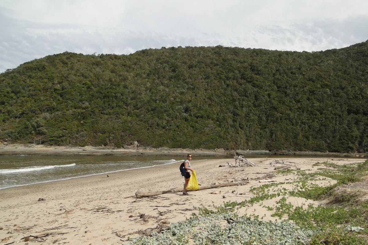 Student picking up litter from a beach