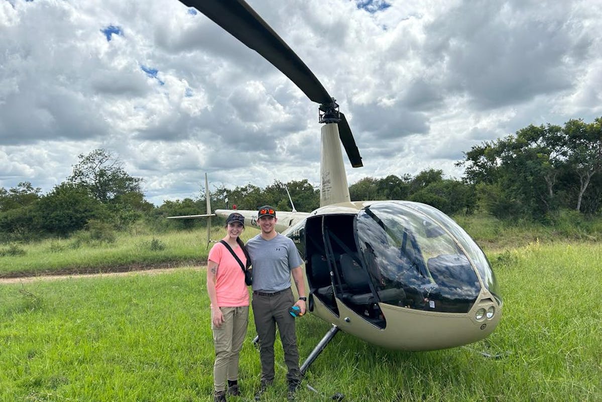 a couple pose in front of a helicopter