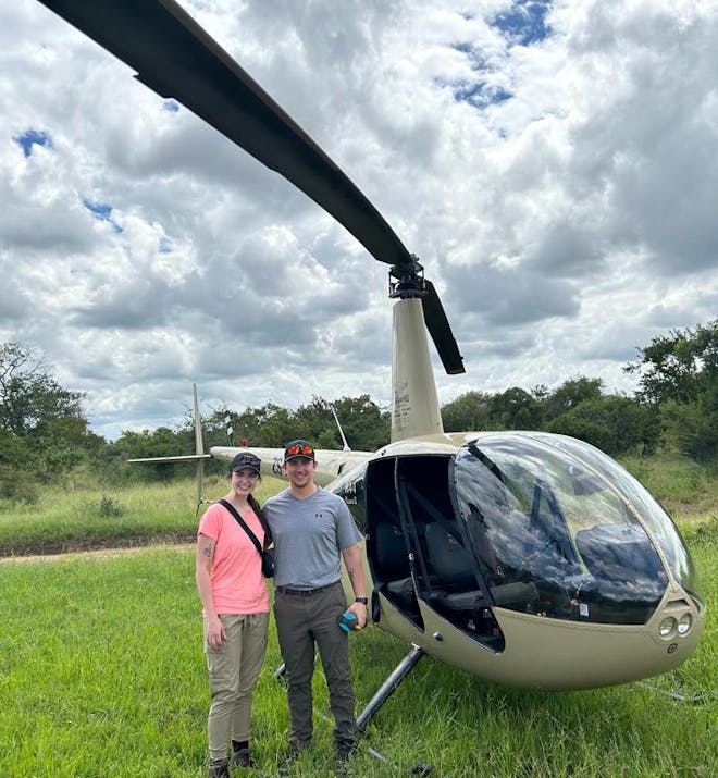 A couple pose in front of a helicopter