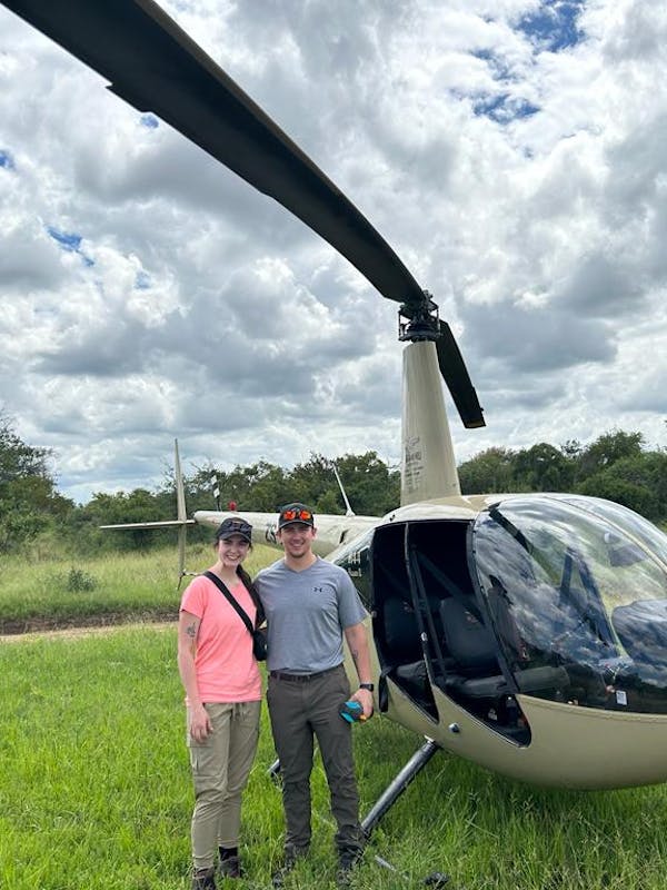 a couple pose in front of a helicopter
