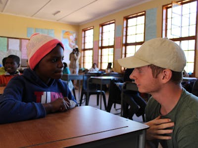 Male ACE student having a conversation with a younger student in the local school