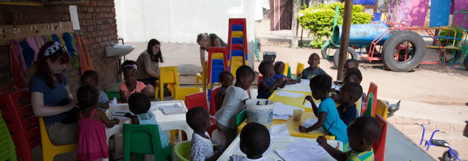 Students engaging with young children at the community school, teaching and learning together