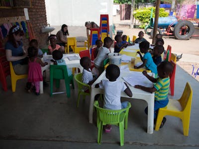 Students engaging with young children at the community school, teaching and learning together