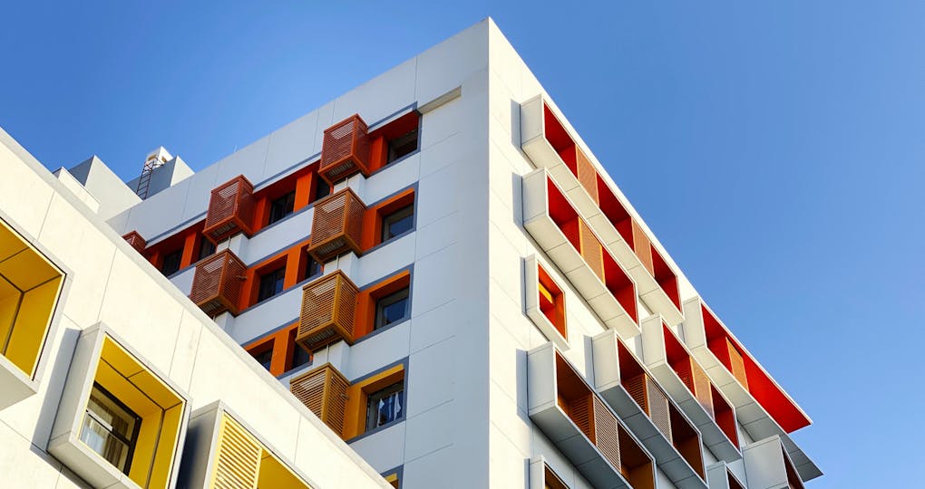 White building with colourful shutters against a clear blue sky.