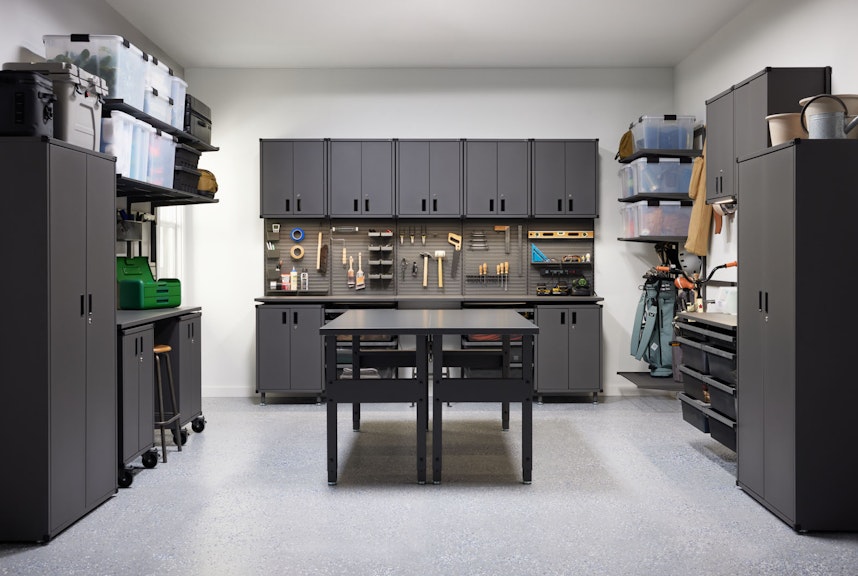 A custom Garage+ By Elfa storage solution featuring cabinets, LED lighting, pegboards, drawers, shelves, storage hooks, and work benches
