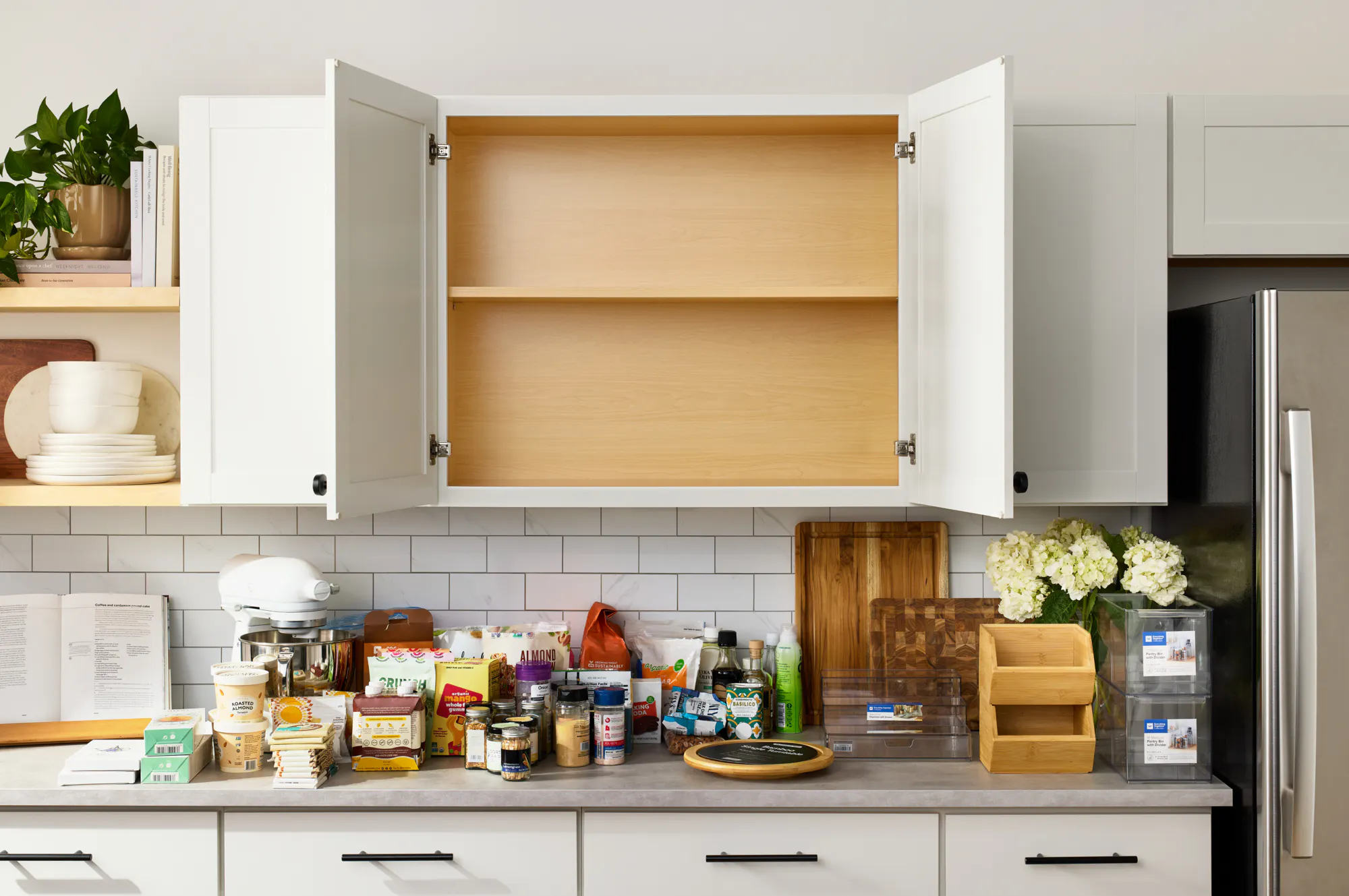 An empty pantry cabinet with its contents laid out on the kitchen countertop