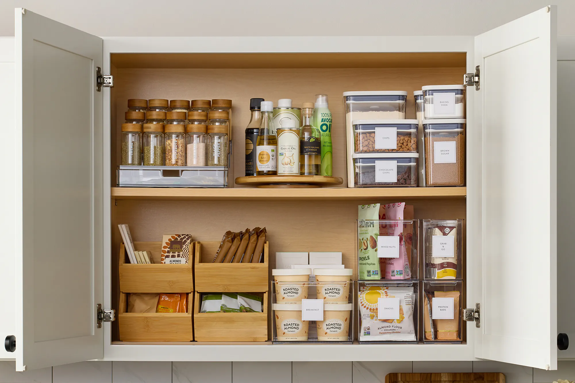 An organized pantry cabinet with airtight containers, stacking bins, a lazy susan, and 3-tier organizer