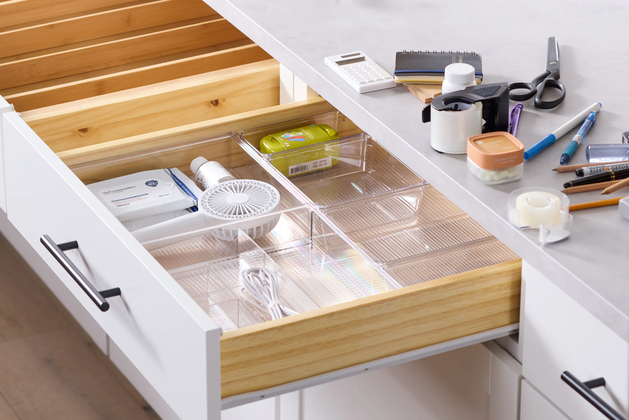 The kitchen junk drawer with contents being added to the drawer organizer