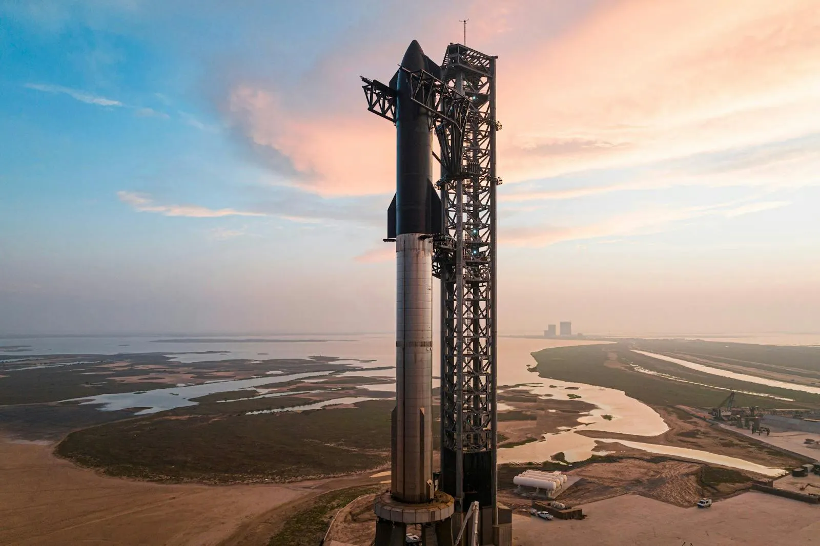 Photograph of Starship stacked on its Super Heavy booster at the launch tower at dawn