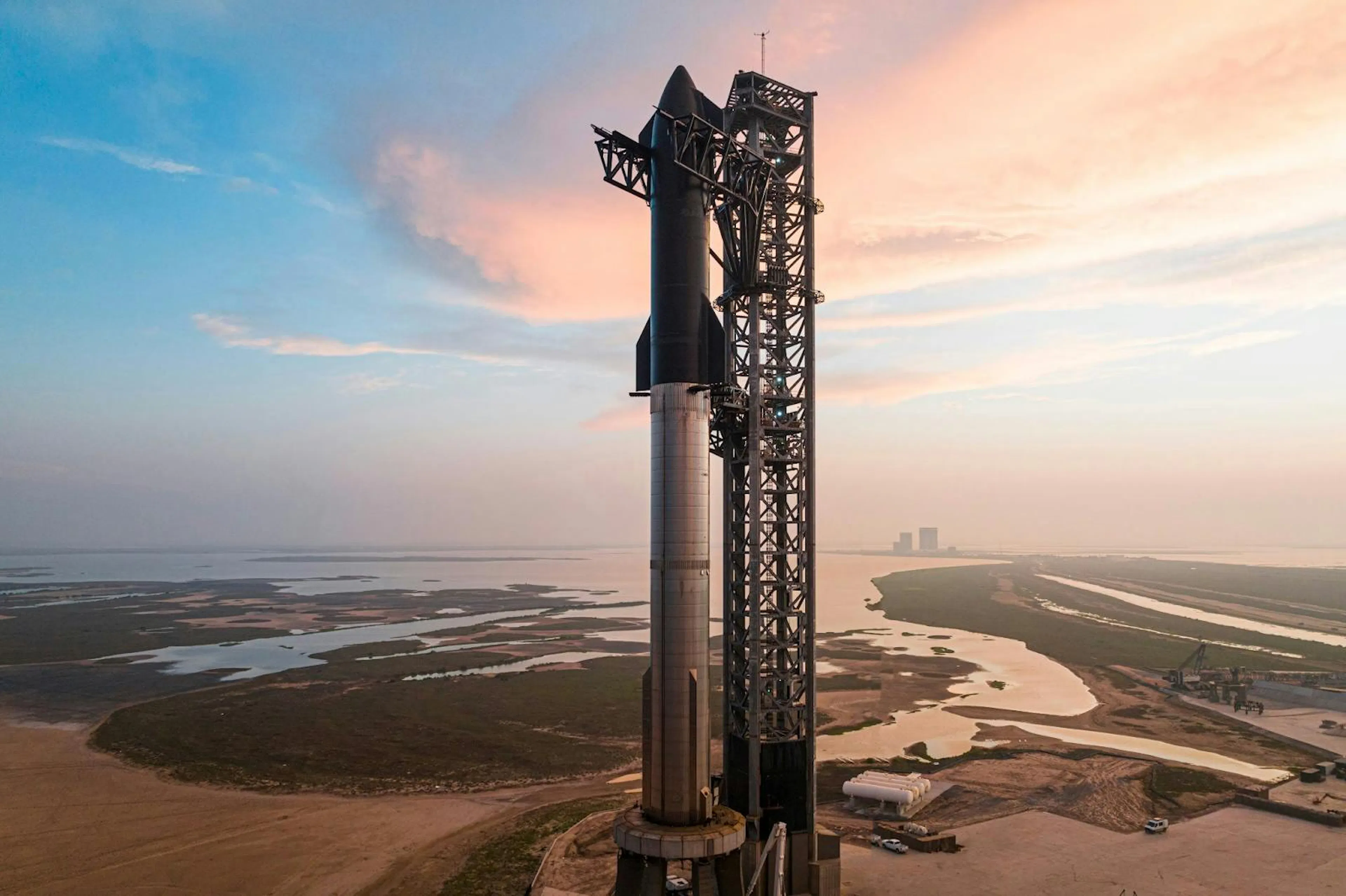 Photograph of Starship stacked on its Super Heavy booster at the launch tower at dawn