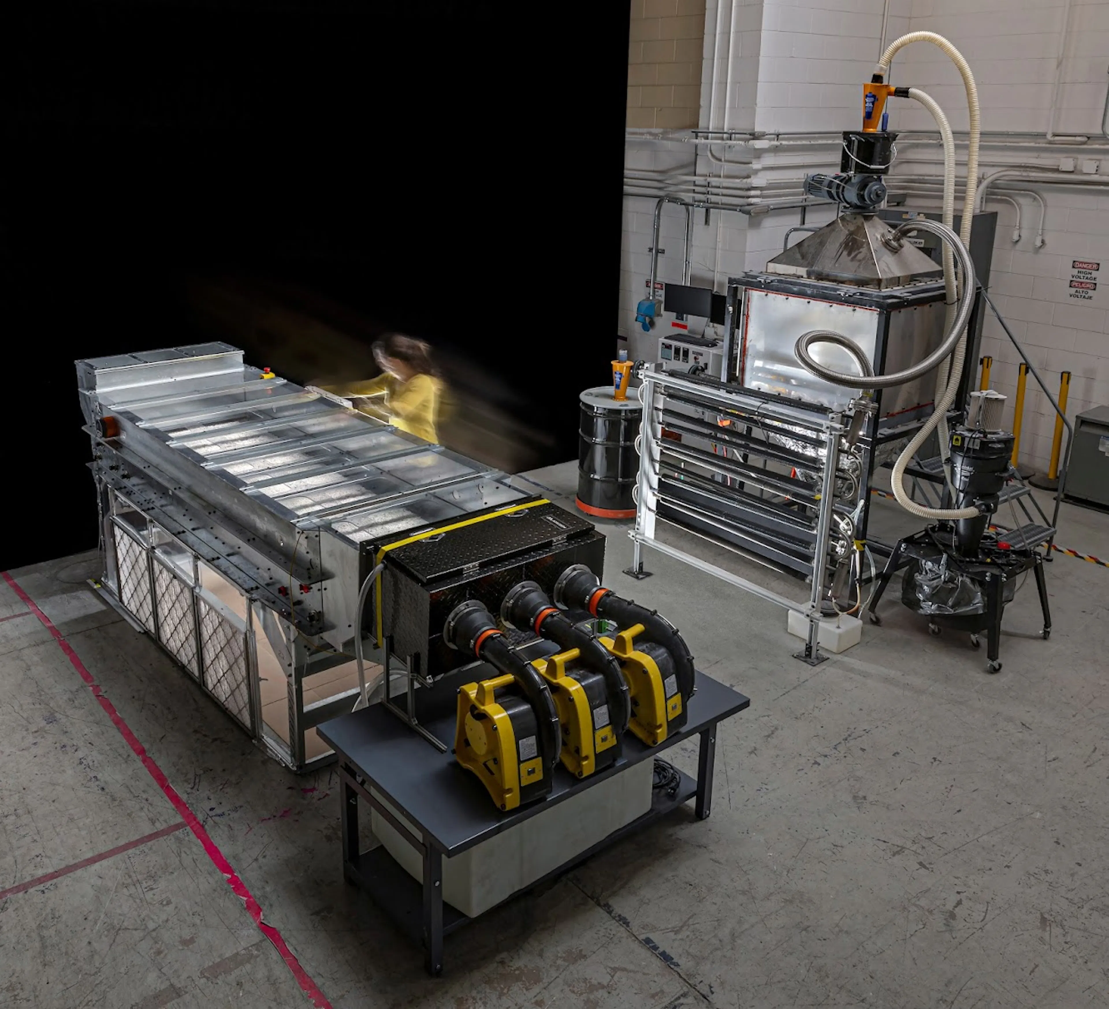 Terraform Industries' direct air capture system in its Burbank workshop, with a long absorber bed with fans, next to a kiln and piping used to regenerate the sorbent