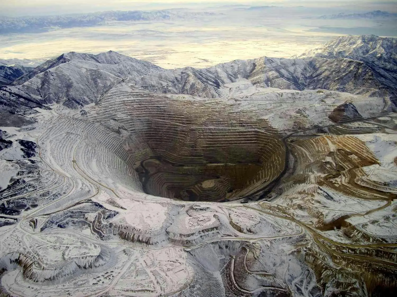 Aerial photograph of a snow-covered open-pit mine, its terraced benches spiralling down to the pit floor