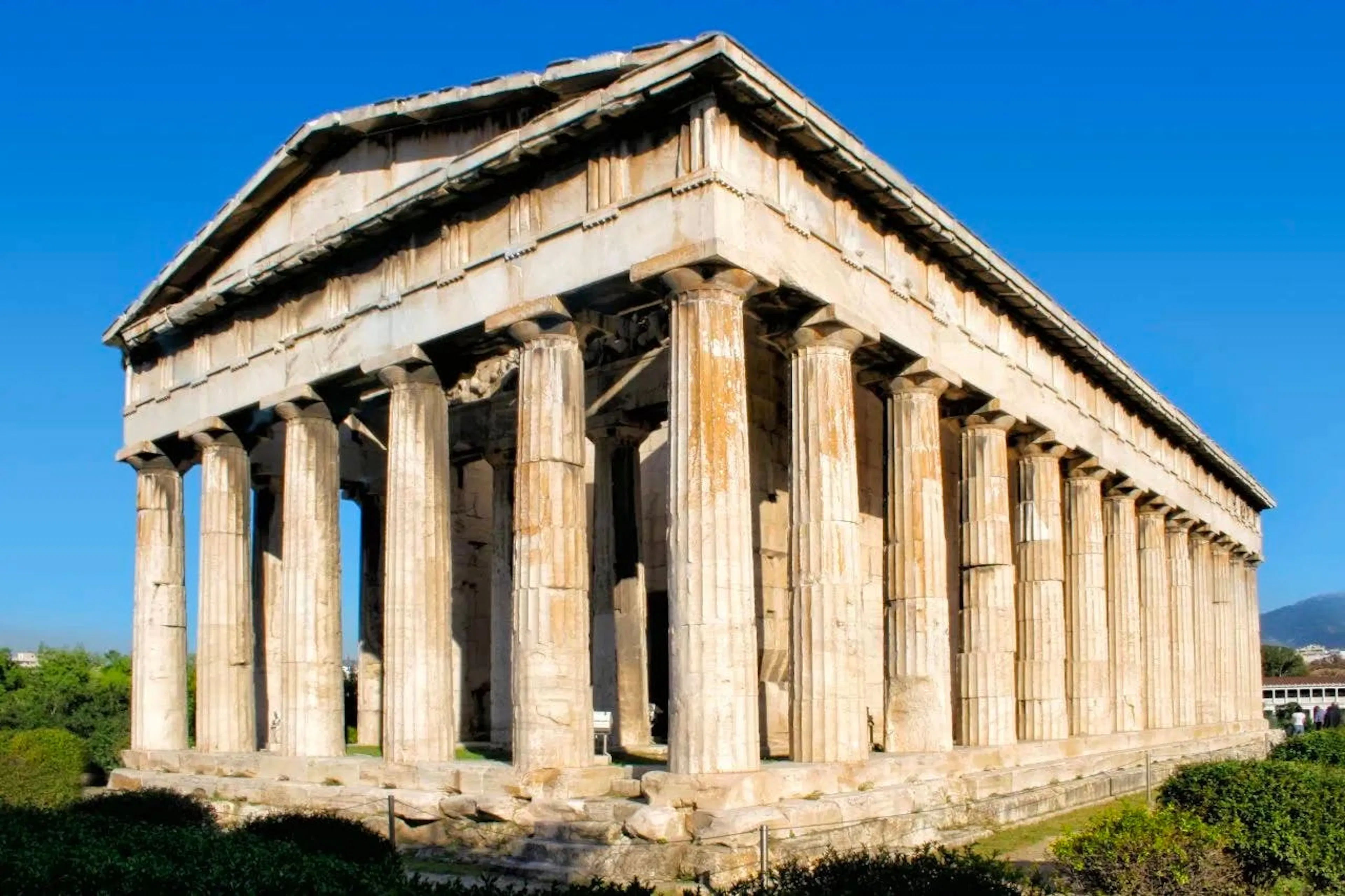 Photograph of a Greek temple, its marble colonnade and pediment intact against a blue sky