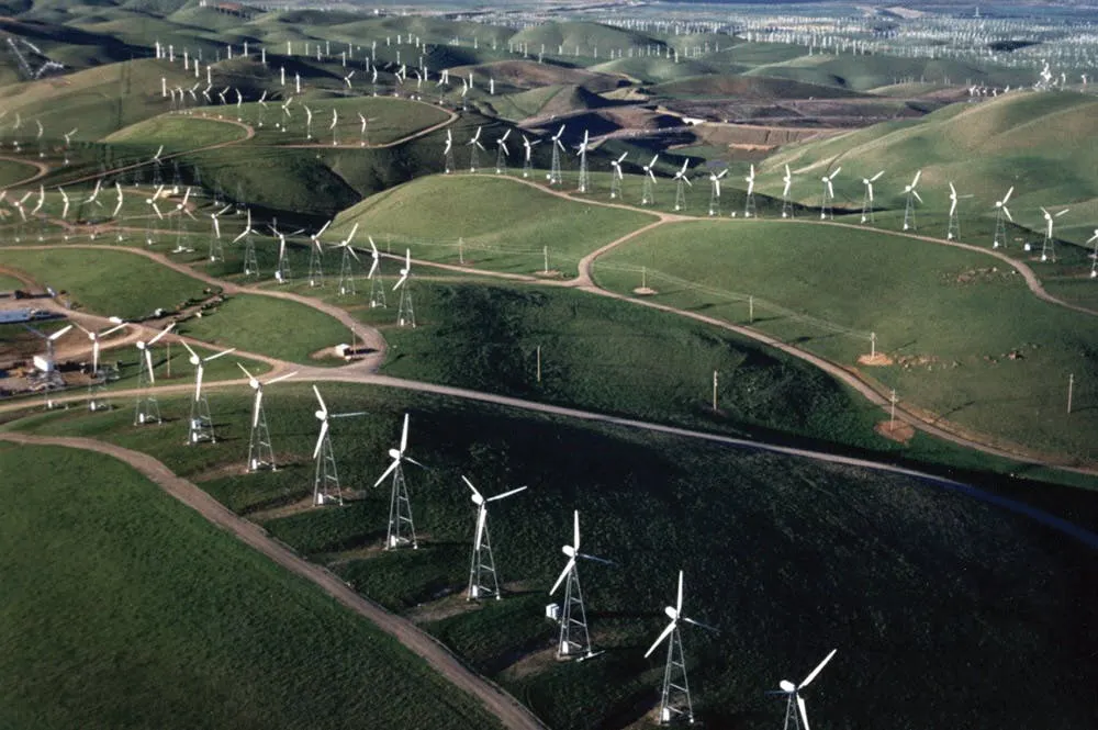 Aerial view of the Altamont Pass wind farm, hundreds of small lattice-tower turbines covering green hills