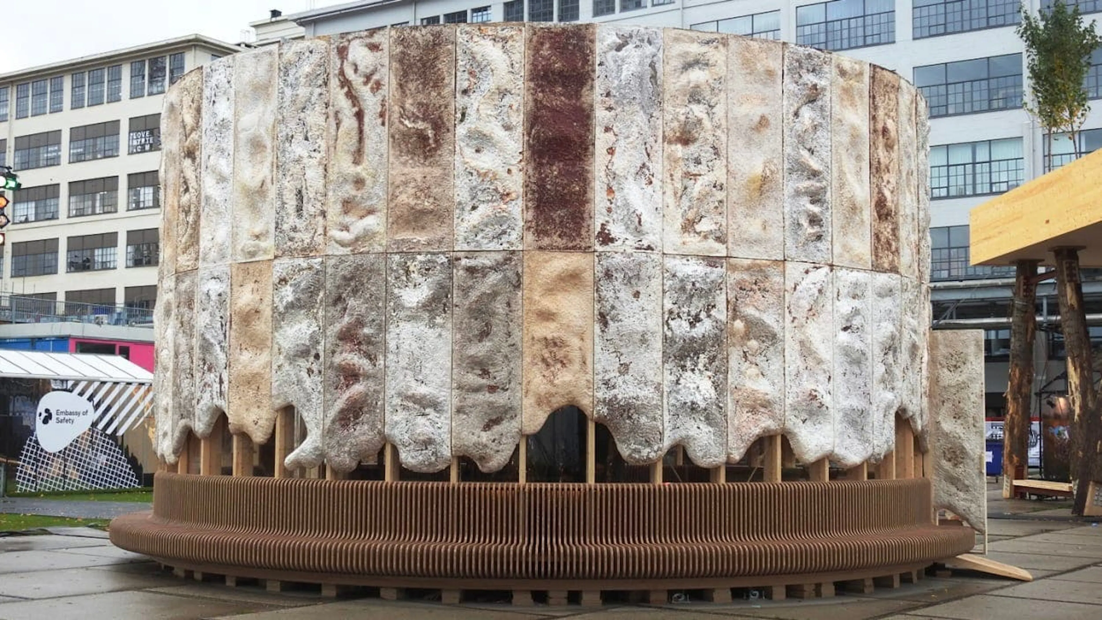 Photograph of a circular pavilion built from mycelium blocks on a timber base in a public square