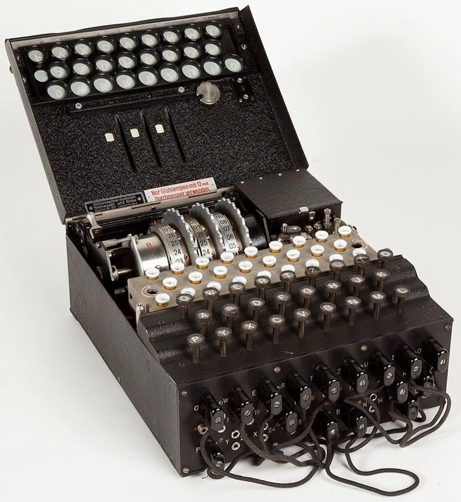 Photograph of a German Enigma machine with its lid open, showing rotors, keyboard and plugboard cables