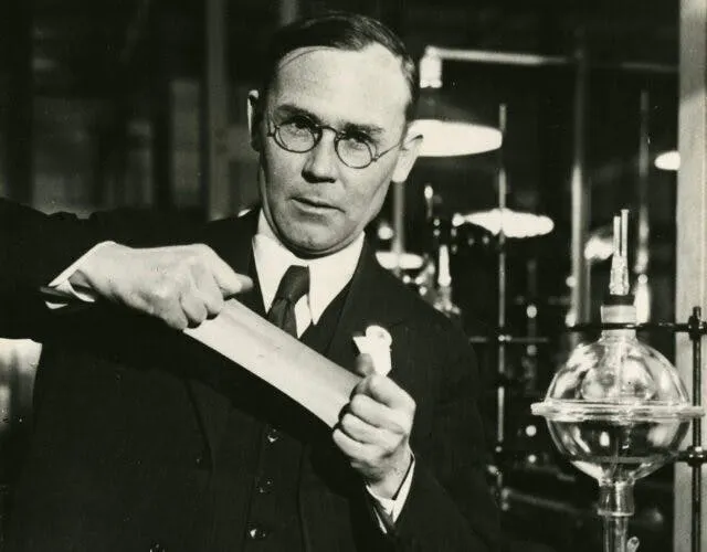 Black-and-white photograph of Wallace Carothers stretching a strip of synthetic polymer in the DuPont laboratory