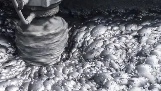 Close-up of a rotating drill bit grinding into pale rock