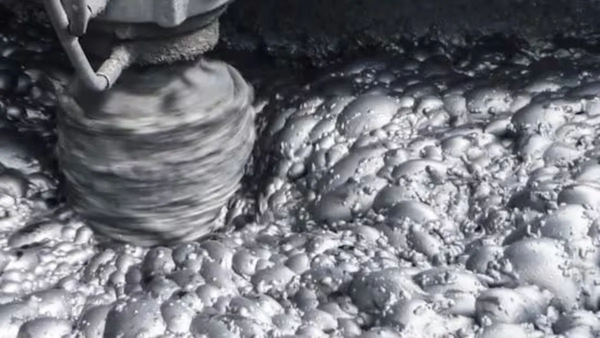 Close-up of a rotating drill bit grinding into pale rock