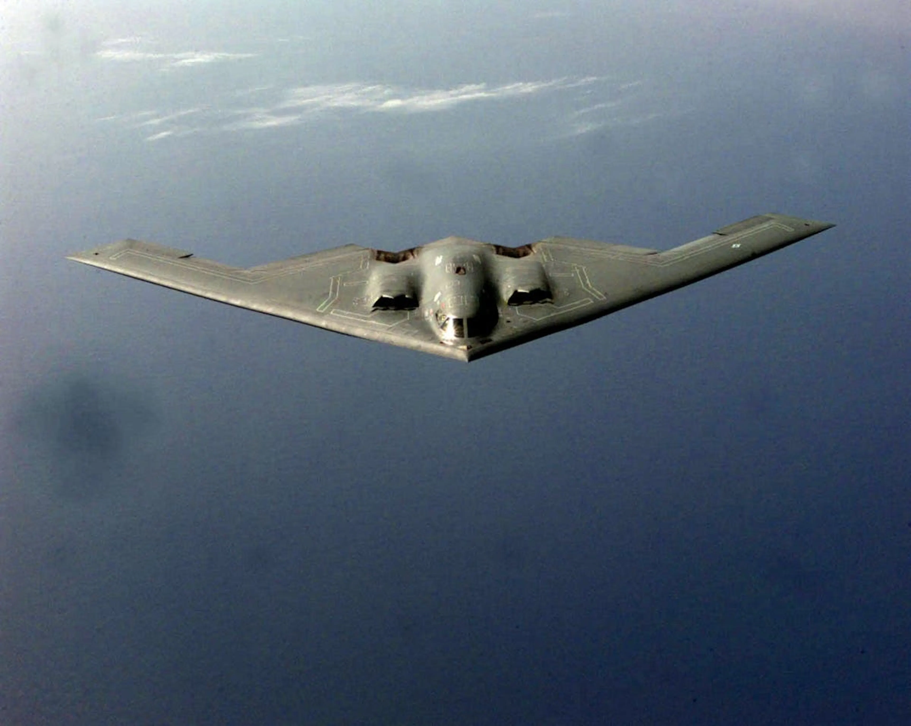 Photograph of a B-2 Spirit flying wing bomber in flight above the sea