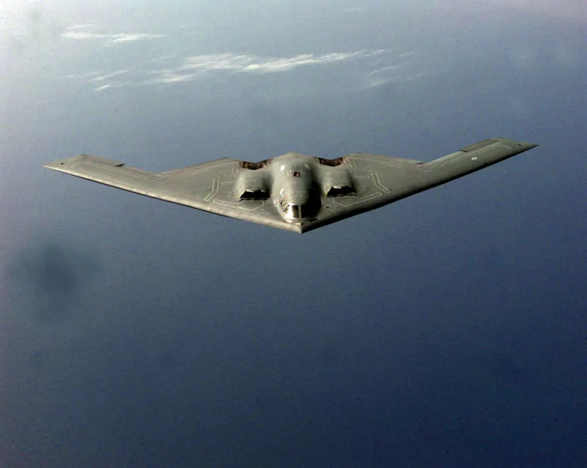 Photograph of a B-2 Spirit flying wing bomber in flight above the sea