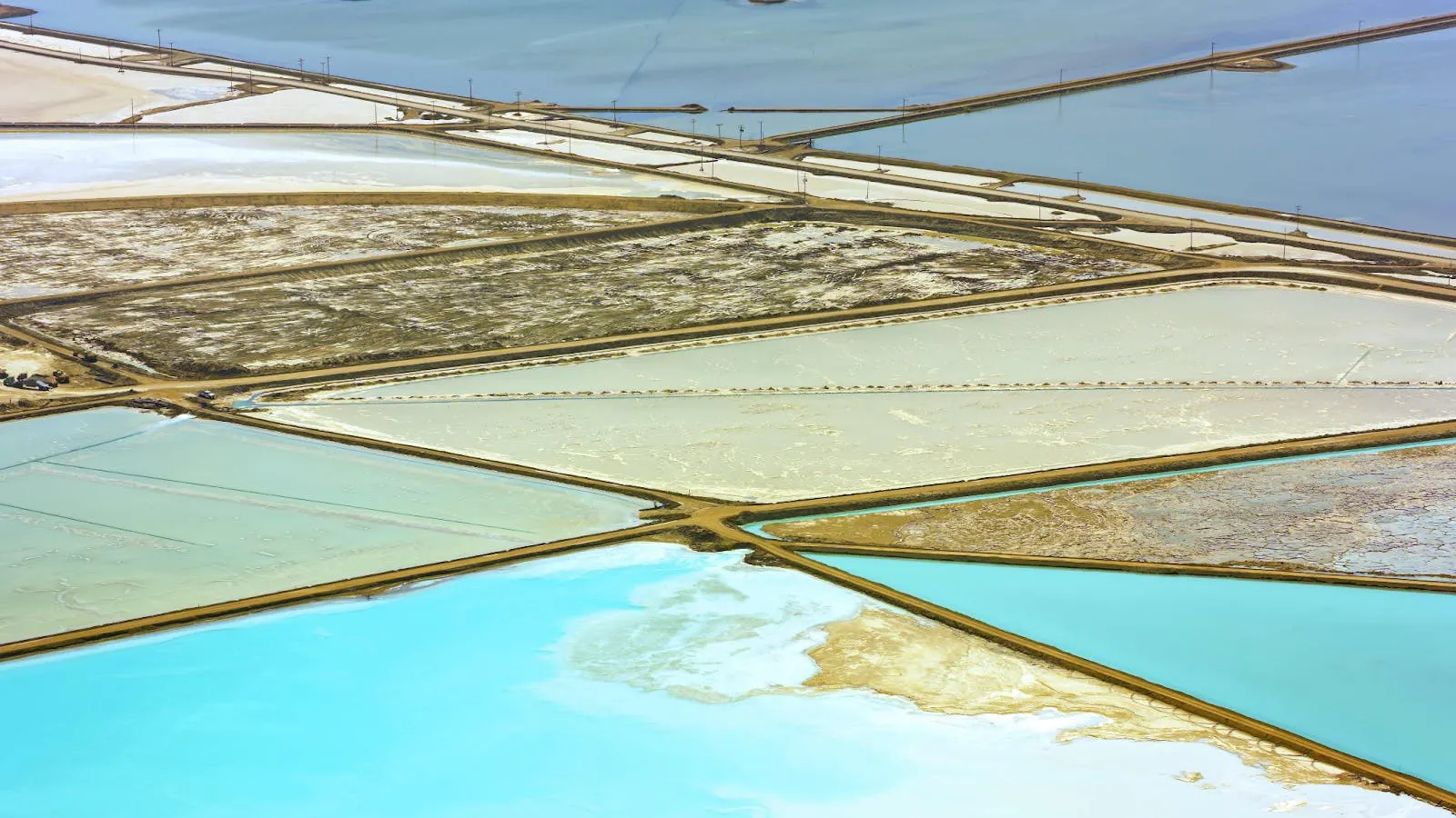 Aerial view of lithium brine evaporation ponds, rectangular basins in turquoise, cream and ochre