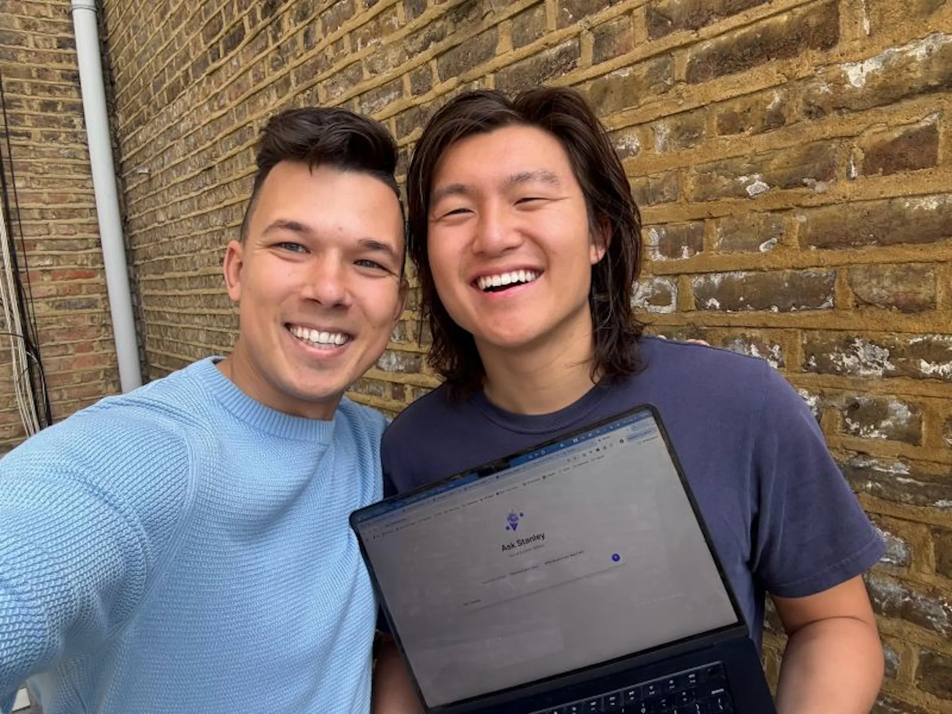 Stan co-founders John Hu and Vitalii Dodonov holding a laptop that shows Stanley's "Ask Stanley" screen.