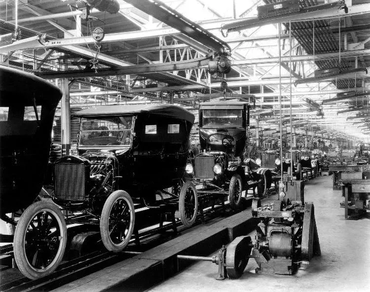 Black-and-white photograph of Ford Model T bodies moving along the moving assembly line