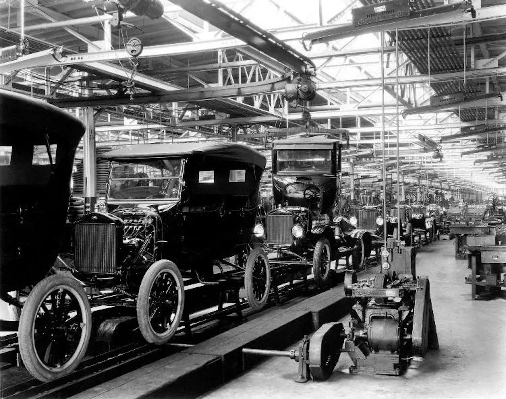 Black-and-white photograph of Ford Model T bodies moving along the moving assembly line