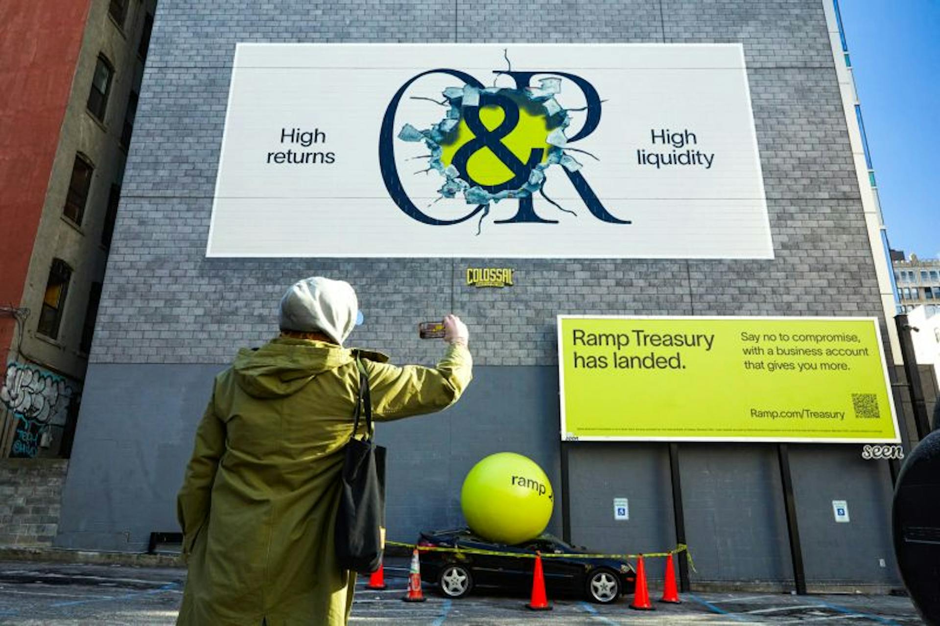 “Ramp Treasury has landed” billboard above a ramp wrecking ball demolishing a sports car