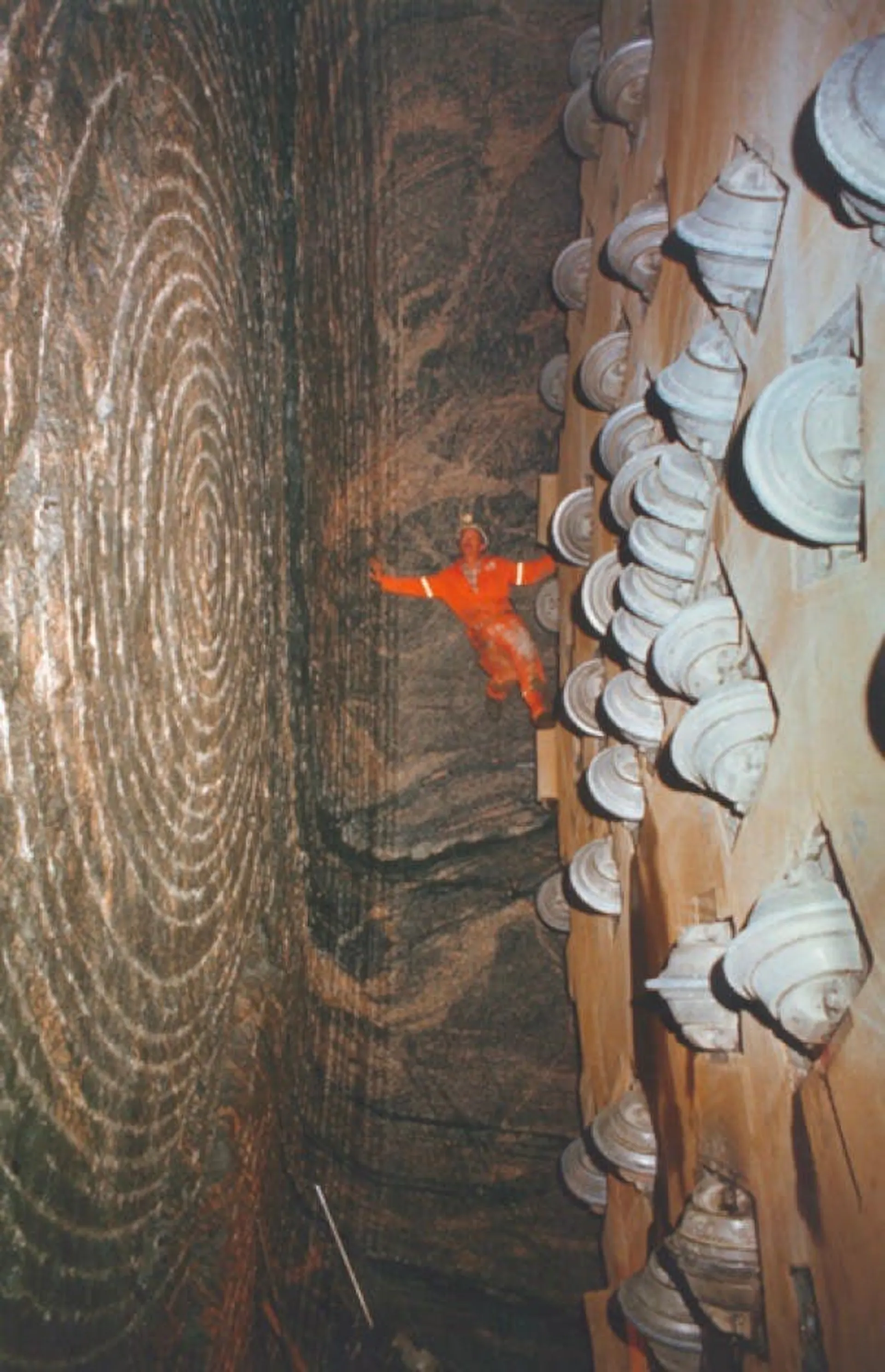 Photograph of a tunnel boring machine's cutter head, disc cutters ringing the face with a worker for scale
