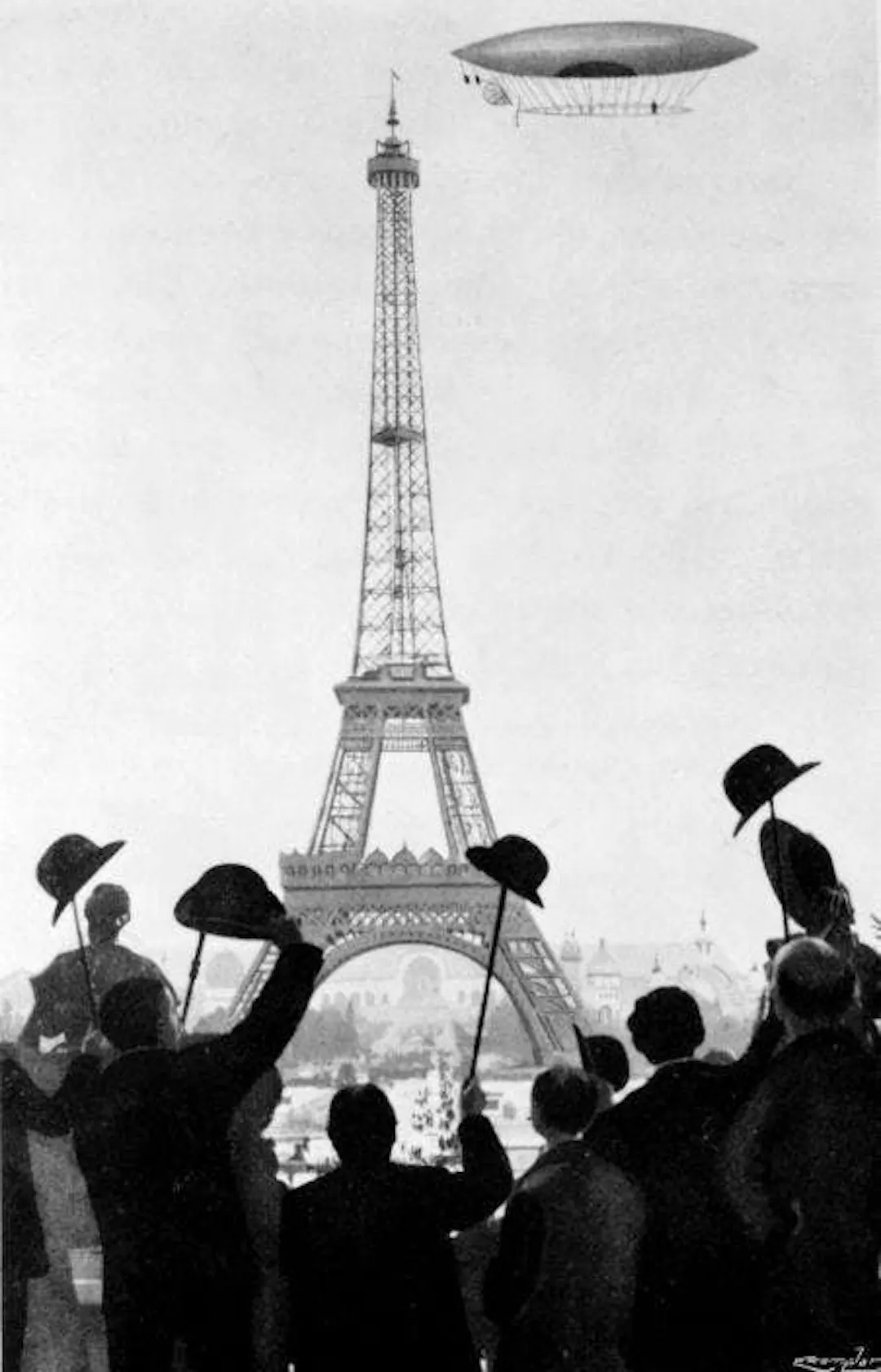 Black-and-white illustration of a crowd in period hats watching an airship circle the Eiffel Tower