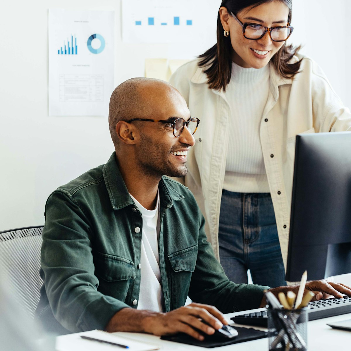 Two people working on a computer together in the office