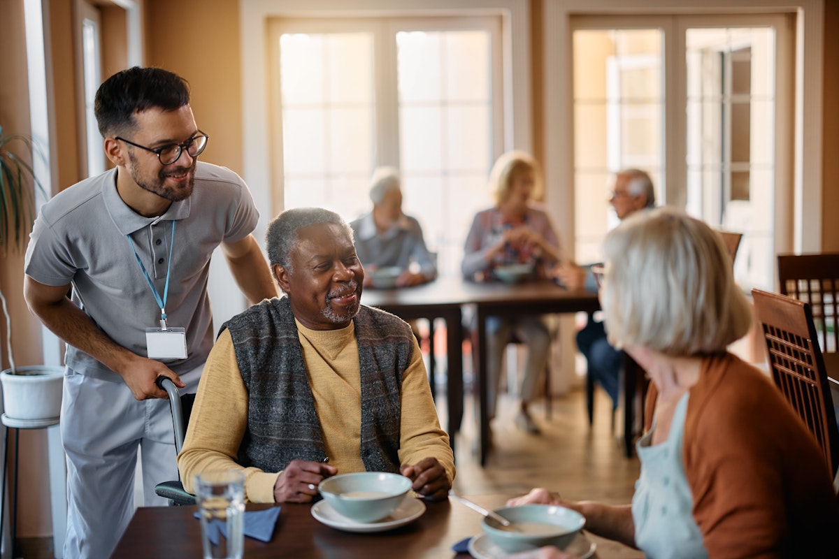 Staff member at care home in dining room with residents