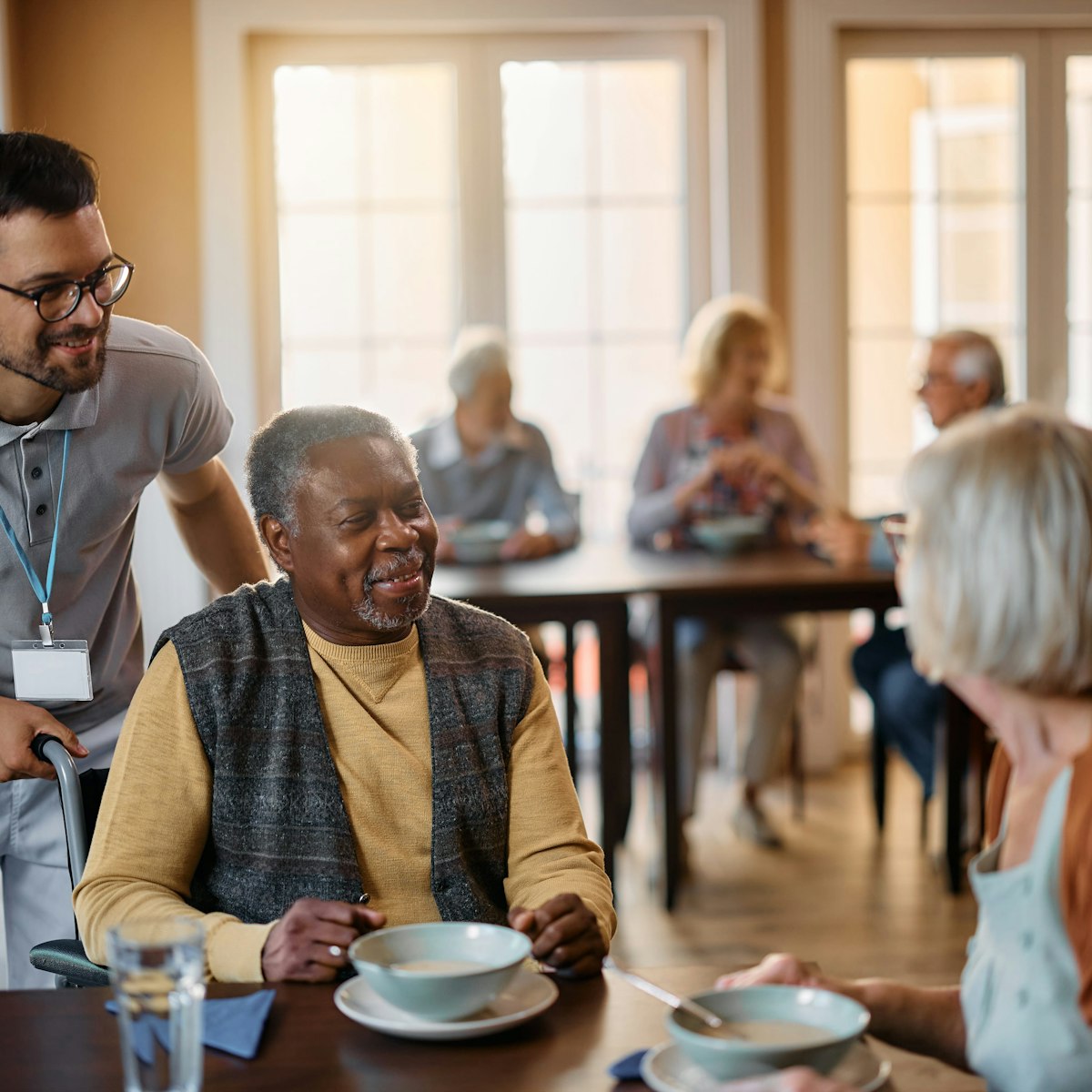 Staff member at care home in dining room with residents