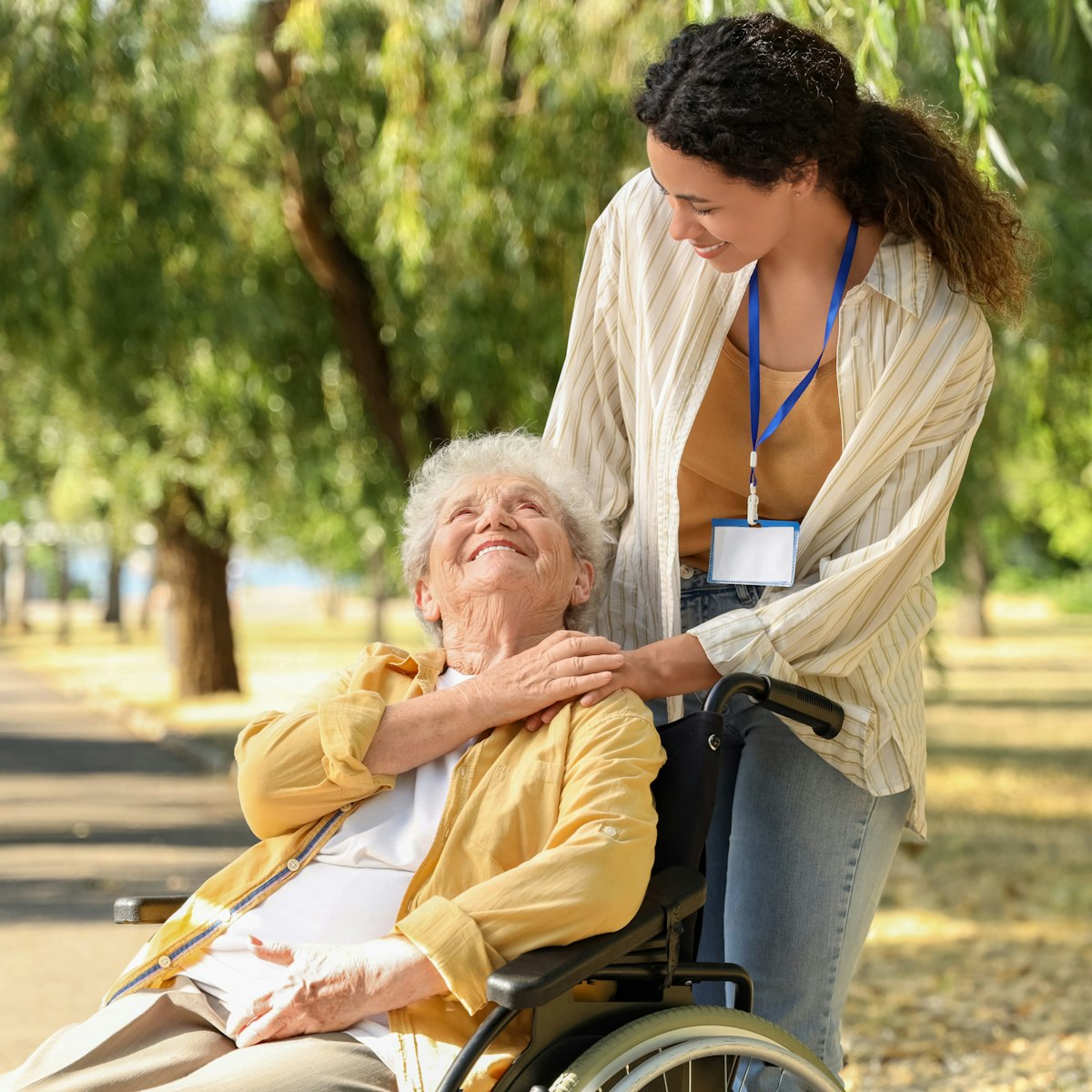 Care worker taking elderly woman for a walk outside in a park