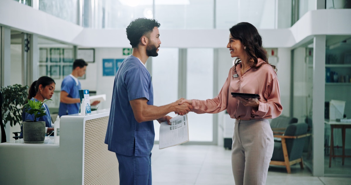 Nurse shaking hands with woman in pink blouse