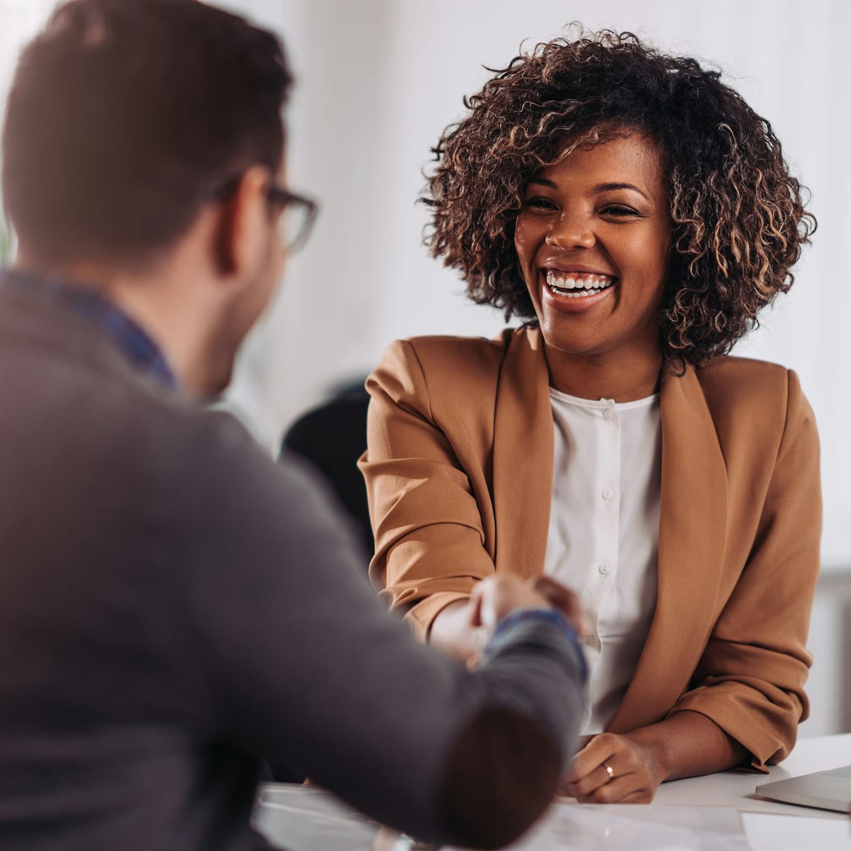 Man and a woman shaking hands over a desk