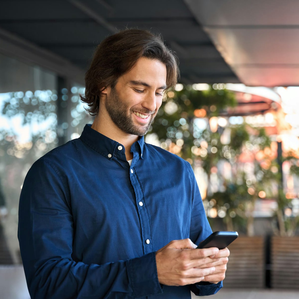 man smiling and looking at his smartphone