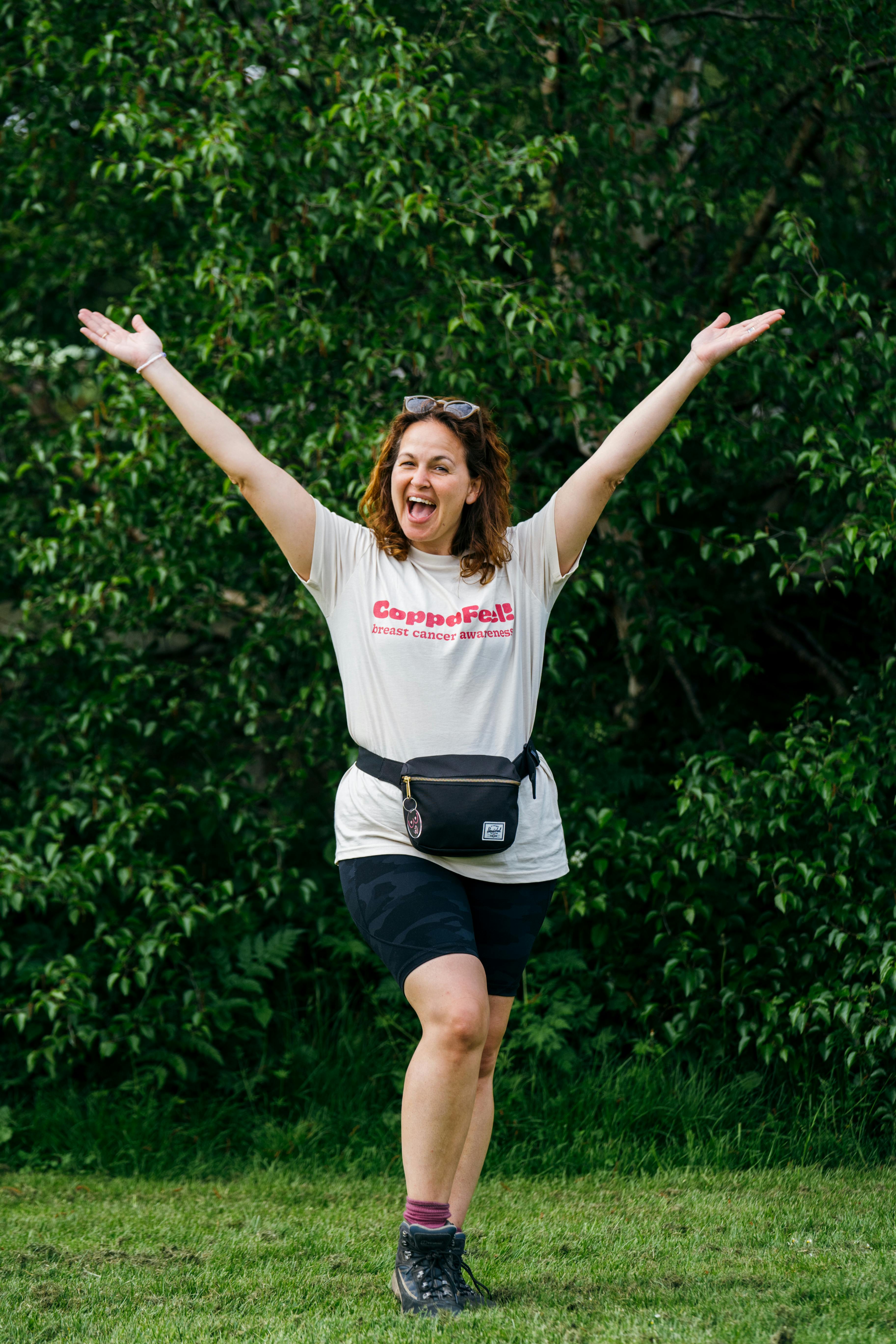 Gi smiling with arms raised, wearing CoppaFeel t-shirt