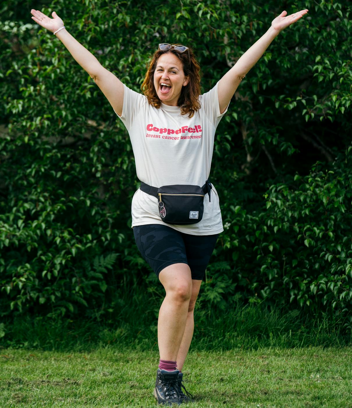 Gi smiling with arms outstretched in a CoppaFeel t-shirt