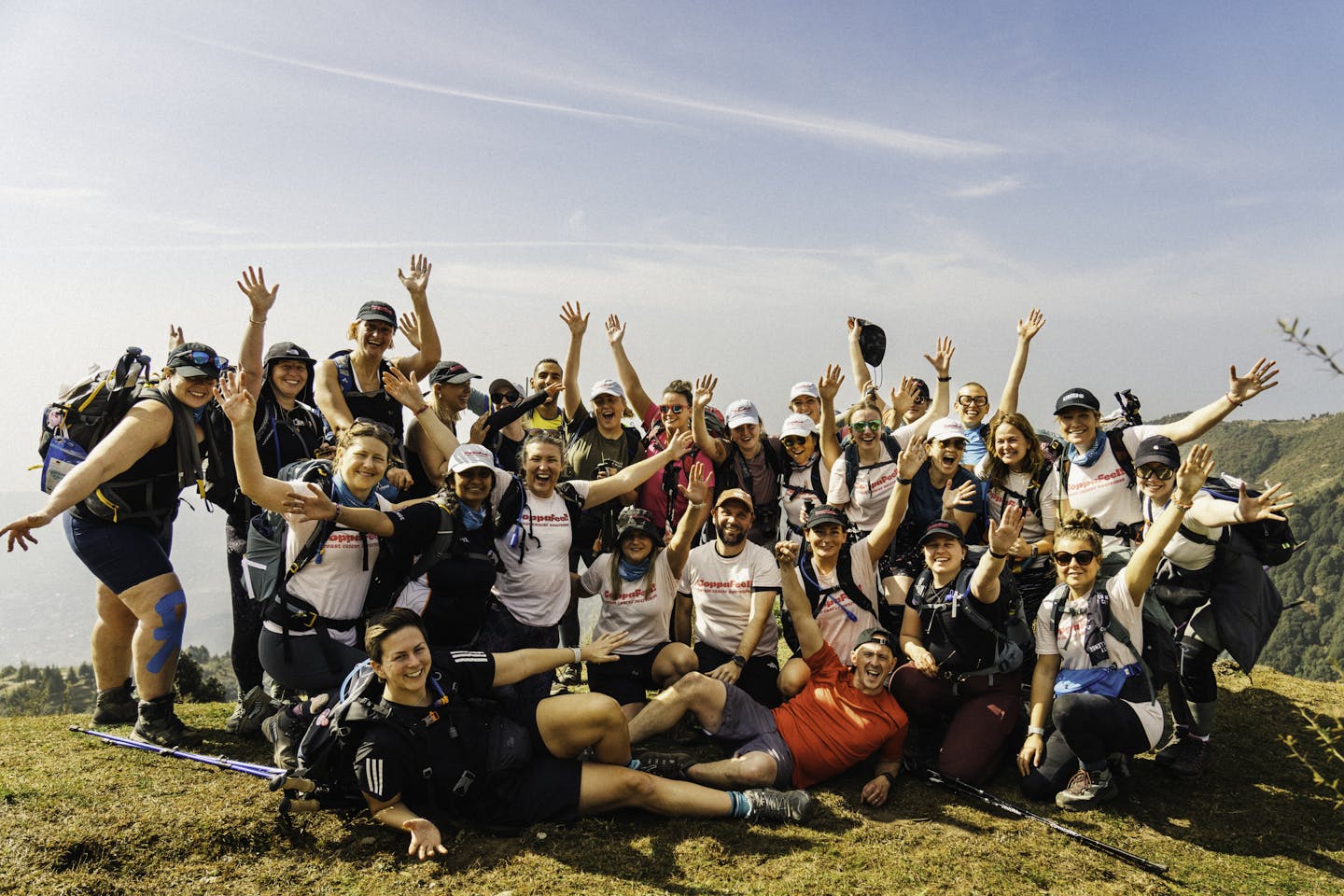 Group of trekkers smiling for a photo in a sunny landscape.