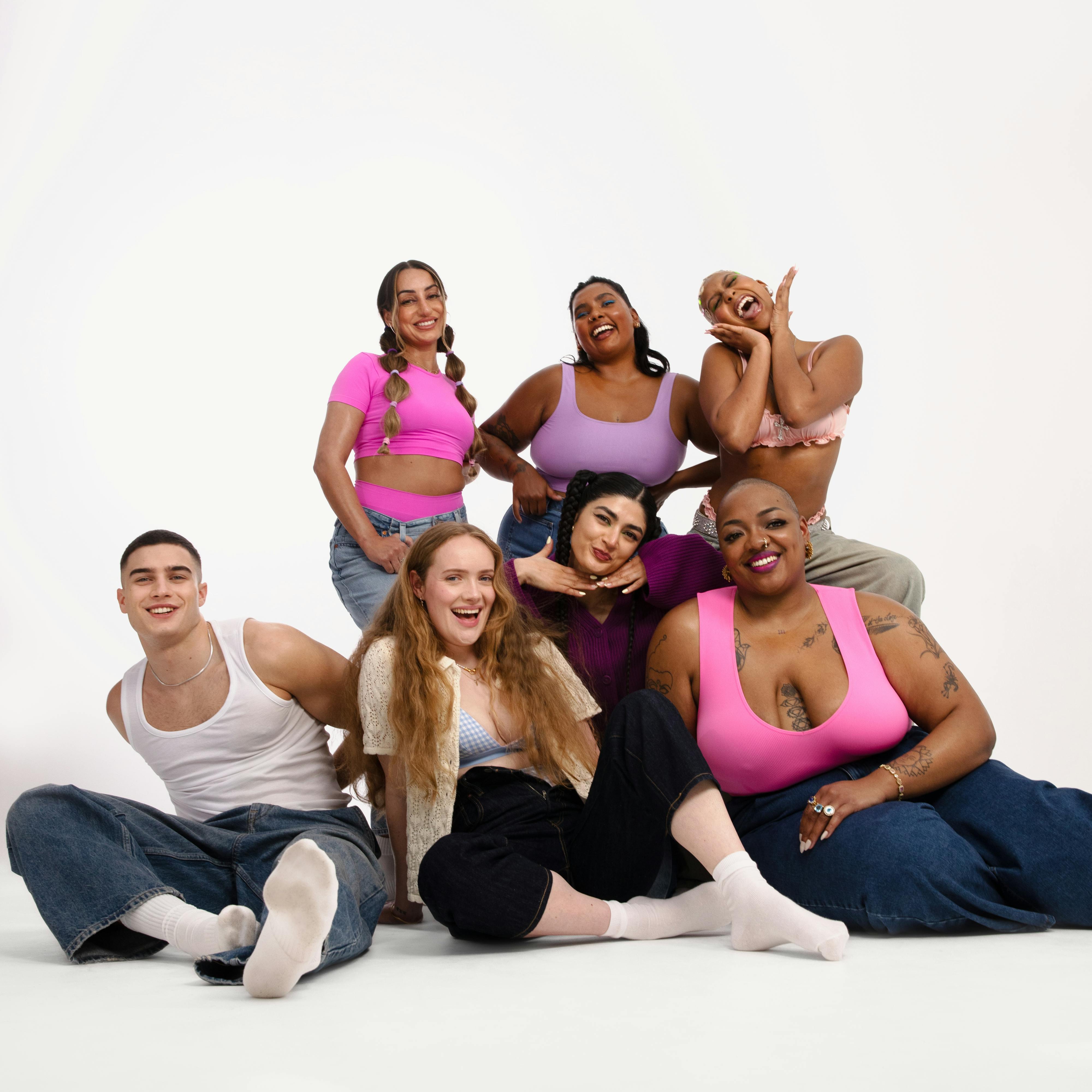 Photo of a group of young people, some sitting and some standing, against a white backdrop.