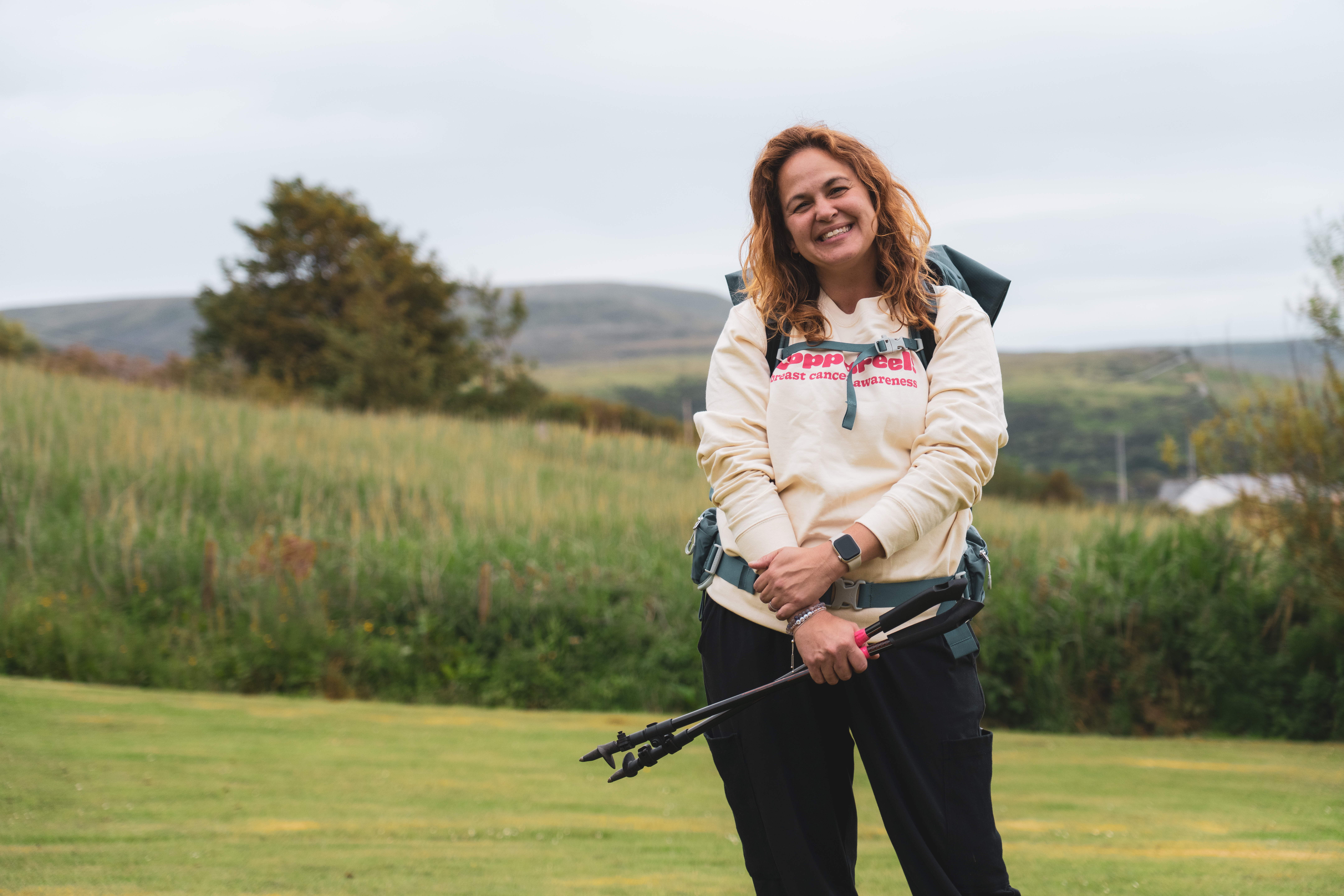 Gi smiling with trekking poles, wearing a CoppaFeel! jumper.