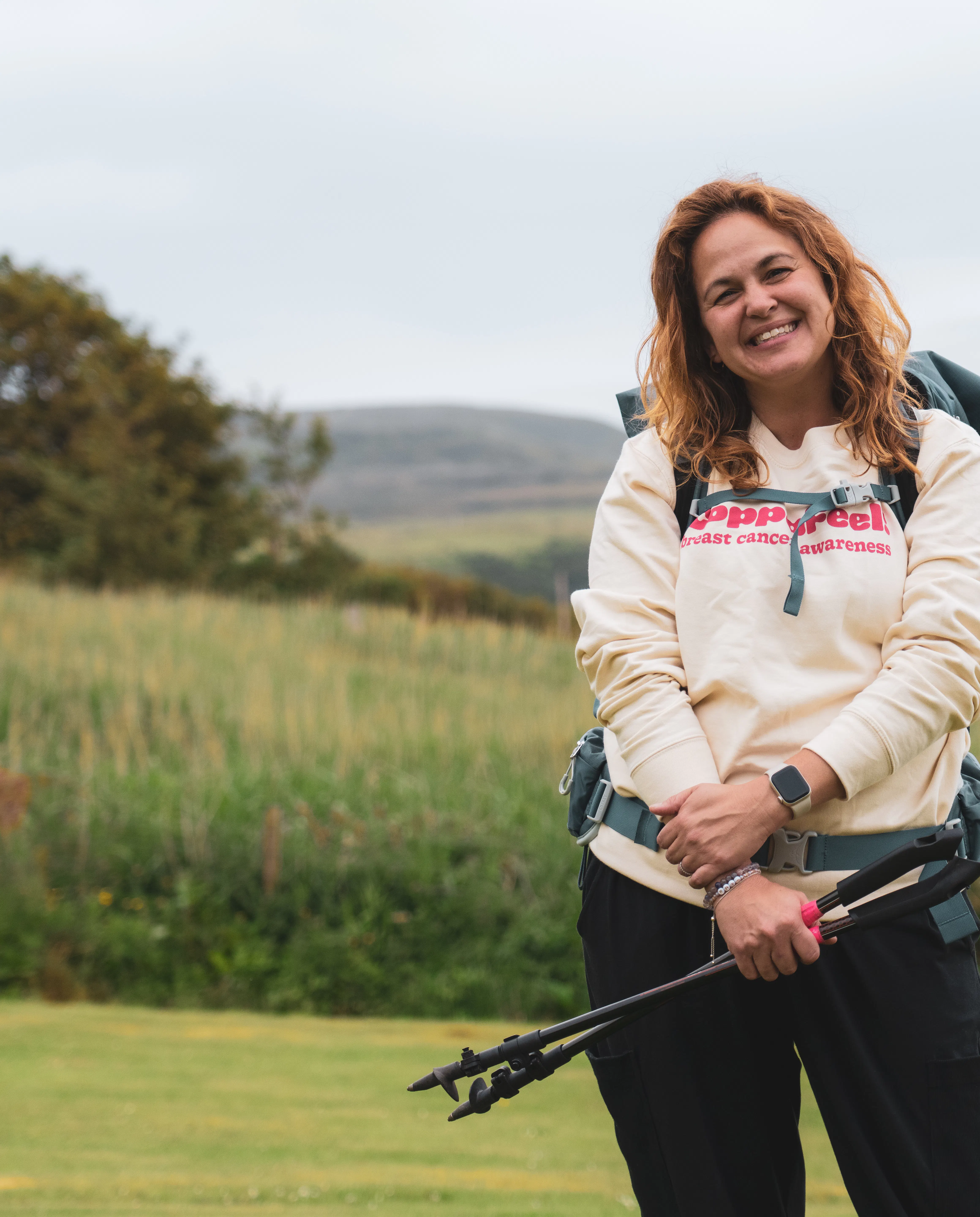 Gi smiling with trekking poles, wearing a CoppaFeel! jumper.
