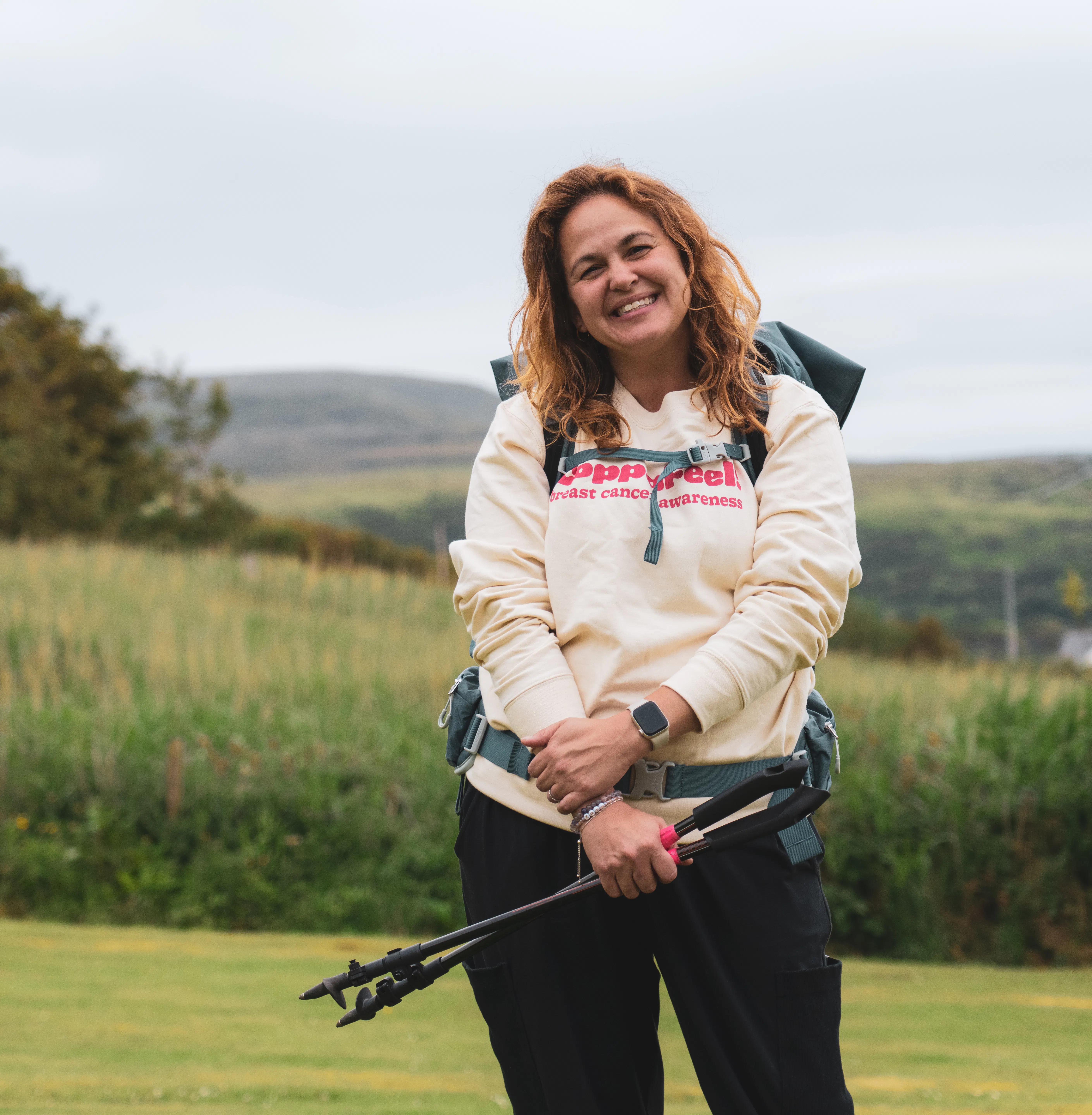 Gi smiling with trekking poles, wearing a CoppaFeel! jumper.